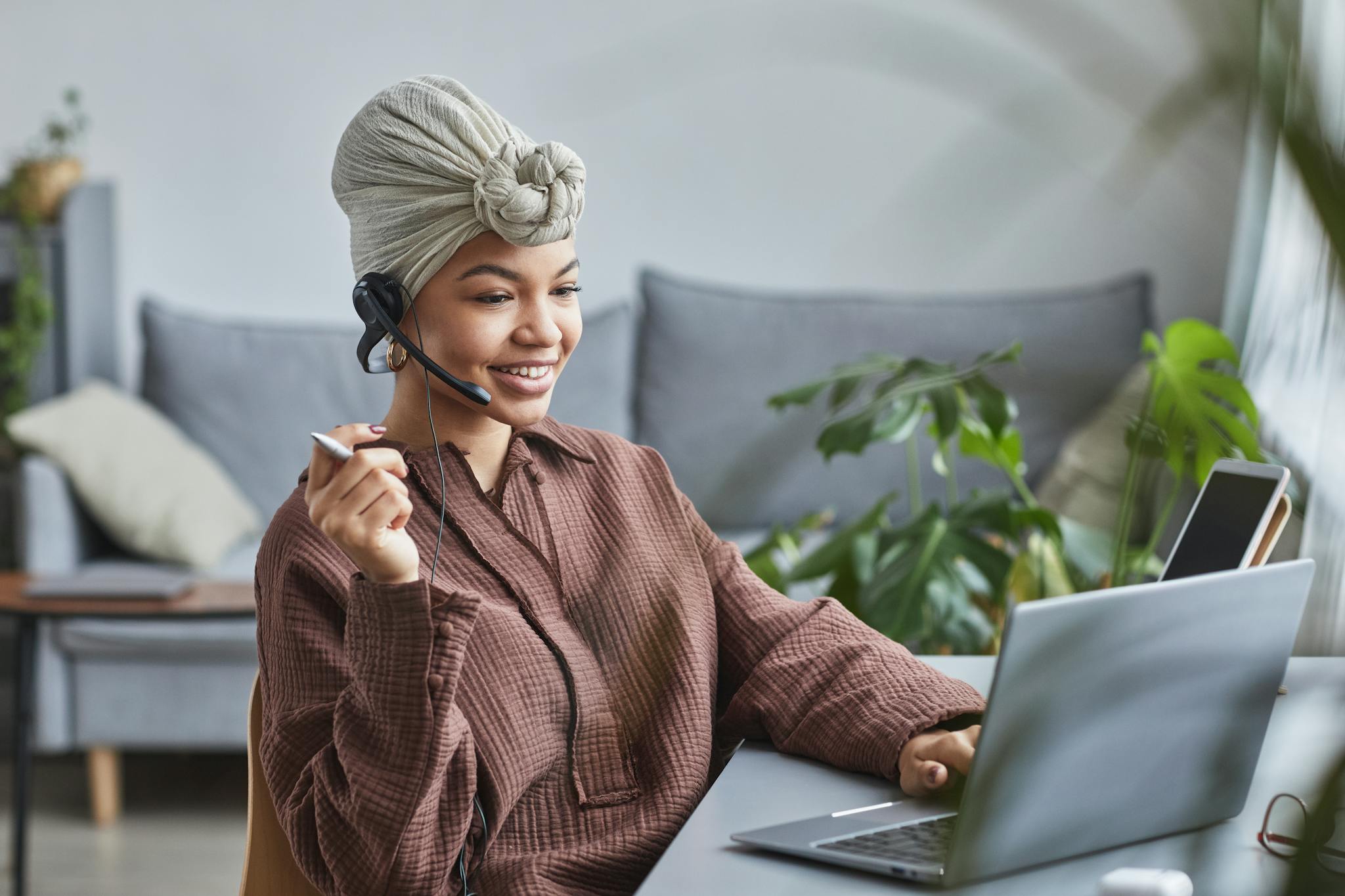 smiling woman in headphones working on laptop